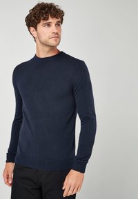 Suéter de punto suave de cuello redondo en color navy, con mangas largas y puños acanalados. Diseño sencillo sin patrones ni adornos.
