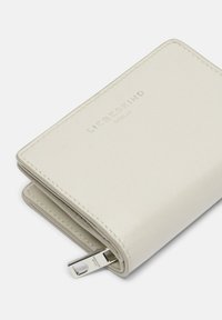 Cartera de cuero blanca con logo en relieve de "LIEBESKIND", textura suave y herrajes de color plateado. Se pueden ver los tiradores de la cremallera y el diseño plegado.