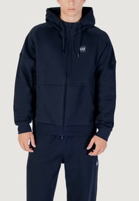 Marineblaue Zip-Hoodie mit Kapuze mit Kordelzug, Taschen vorne und Logo-Patch. Hergestellt aus weichem Stoff mit lässigem Schnitt und gerippten Bündchen.