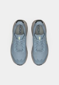 Ζευγάρι ανοιχτό μπλε παπούτσια τρεξίματος HOKA με γκρίζες σόλες, που φαίνονται από πάνω σε λευκό φόντο.