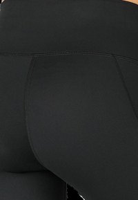 Black high-waisted leggings with a smooth, stretchy fabric, featuring reinforced seams and a close-fitting design. No patterns or accents visible.