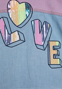 Denimstoff med en lys blå nyanse, som har et flerfarget paljetthjerte og dristig, tredimensjonal "KJÆRLIGHET"-skrift i forskjellige farger.