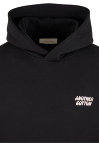 Felpa nera in cotone con tasca a marsupio. Presenta un logo rosa "ANOTHER COTTON" sul petto. Vestibilità classica con cappuccio regolabile.
