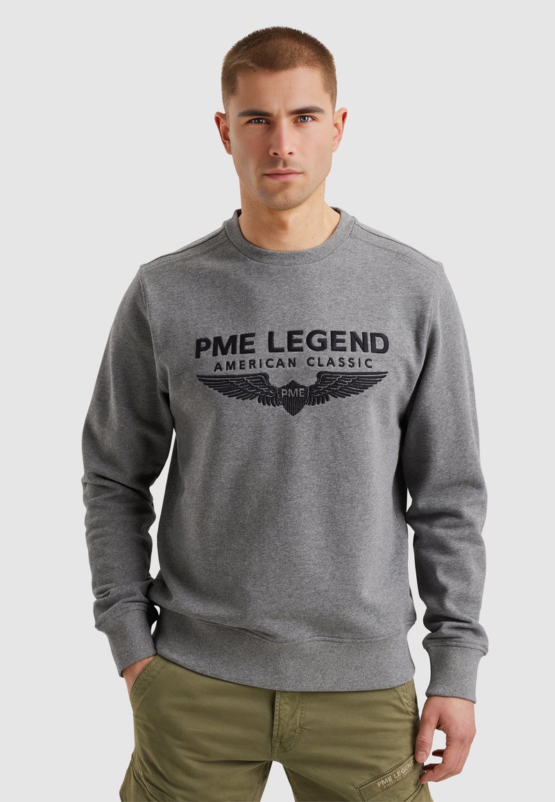 Sudadera gris con cuello redondo, que presenta el texto en relieve "PME LEGEND American Classic" y gráficos de alas en la parte frontal. Mangas largas.