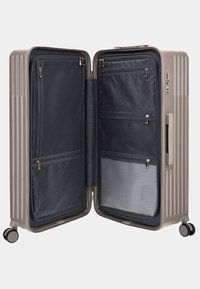Valigia rigida in taupe metallico, con un interno zip con compartimenti in rete e un manico robusto, montata su quattro ruote.