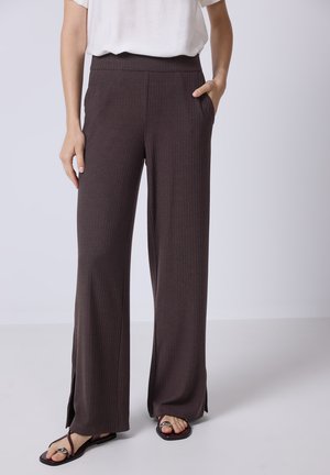 Dark brown wide-leg pants in ribbed texture with side slits and pockets, paired with black flip-flops. Casual look with elastic waist.
