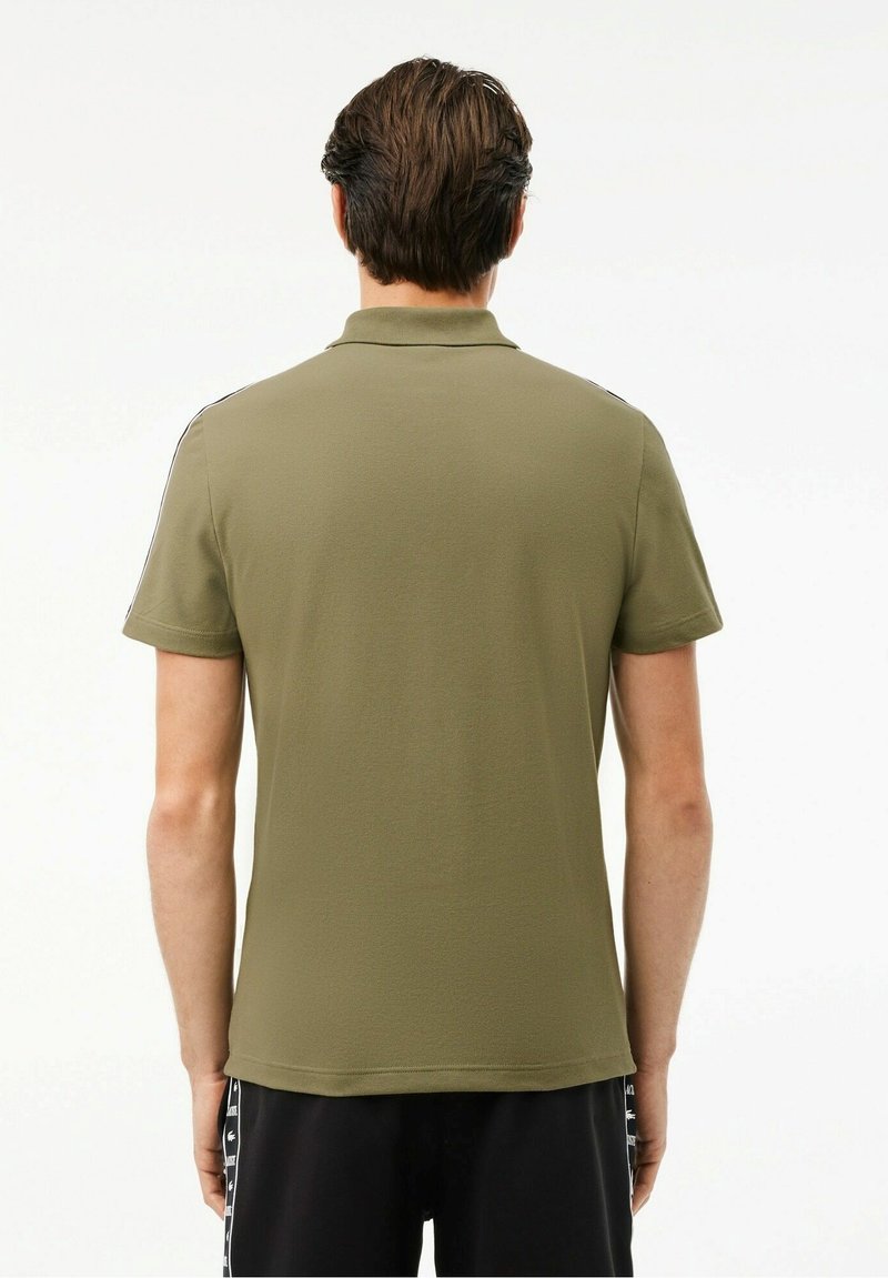 Polo olive en coton, avec des manches courtes et un col classique. Design simple sans motifs ni accents supplémentaires.