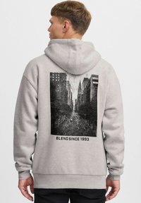 Hoodie gris clair avec un imprimé graphique noir représentant une scène de rue au dos, accompagné du texte "BLEND SINCE 1993" sous l'image.