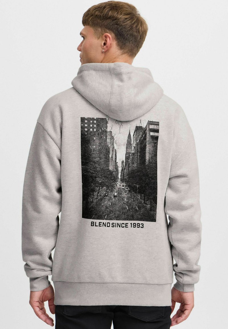 Hoodie gris clair avec un imprimé graphique noir représentant une scène de rue au dos, accompagné du texte "BLEND SINCE 1993" sous l'image.