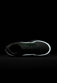 Black sneaker with a breathable mesh upper, reflective white midsole, and green accents. Features laces and a padded collar for comfort.