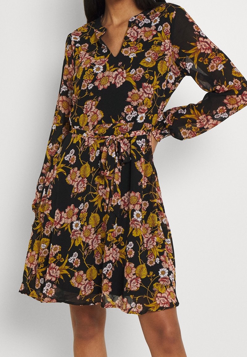 Schwarzes Kleid mit langen Ärmeln, floraler Druck in Rosa, Weiß und Gelb, V-Ausschnitt, geraffte Taille mit Bindeband, luftiger Rock, leichtes Material.