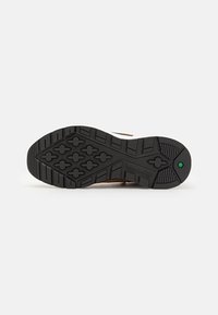 Black rubber shoe sole with textured grip pattern, featuring a green accent and a logo. Designed for durability and traction on varied surfaces.