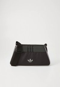 Melna pastnieka soma ar tīkla paneli, baltām akcentēm un regulējamu siksnu. Tās rotā trīs vertikālas svītras un centrā izvietots logotips.