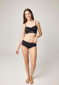 Schwarzes Spitzen-Bralette mit verstellbaren dünnen Trägern und gezackten Kanten, kombiniert mit schwarzen nahtlosen High-Waist-Slips mit glatter Textur.