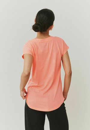 T-shirt met korte mouwen in een levendige koraalkleur. Zachte stof, comfortabele pasvorm, afgeronde zoom en opgerolde mouwen. Achteraanzicht toont een gladde structuur en stiksels.