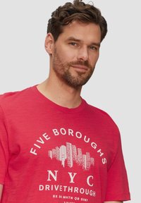 Rotes Baumwoll-T-Shirt mit Rundhalsausschnitt, kurzen Ärmeln und weißem Aufdruck: "FIVE BOROUGHS NYC DRIVETHROUGH" mit einer Skyline-Grafik.