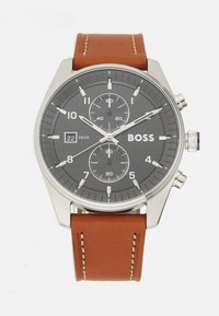 Orologio in acciaio inox argentato con quadrante grigio scuro, caratteristiche cronografiche, cinturino in pelle marrone con cuciture bianche. Resistente all'acqua fino a 5 bar.