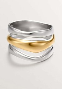 Tres anillos entrelazados: dos de plata pulida y uno de oro mate. Los anillos presentan diseños suaves y ondulados con diferentes anchos.