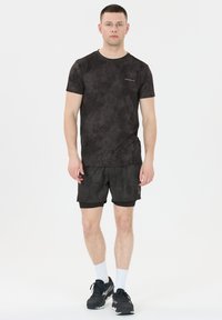 Musta urheilu paita, jossa on hillitty sotilasmuoti, yhdistettynä yhteensopiviin shortseihin. Valmistettu kevyestä kankaasta, jossa on pyöreä kaula-aukko.