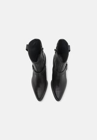 Black leather ankle boots with pointed toes, smooth texture, side zip closure, and decorative strap detail around the ankle.
