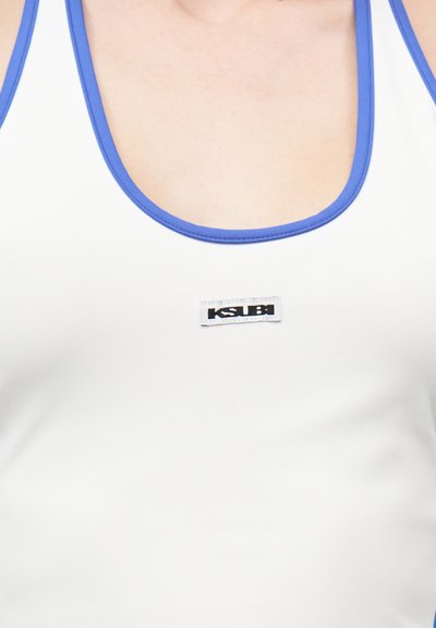 Κοντινό πλάνο λευκού αμάνικου τοπ με μπλε περίγραμμα και μικρό λογότυπο Ksubi στο κέντρο του στήθους.