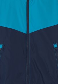 Huvtröja med en färgblockdesign i turkos och marinblå, med dragkedjestängning, två sidofickor och kontrasterande sömmar.