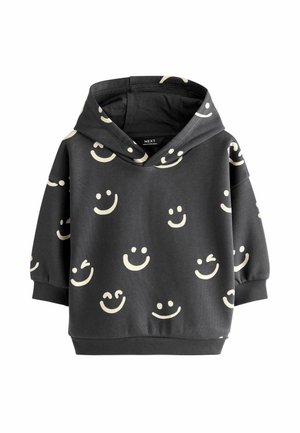 Sweatshirt à capuche en tissu gris foncé avec un motif de visages souriants couleur crème. Poignets et ourlet côtelés, avec une coupe décontractée.