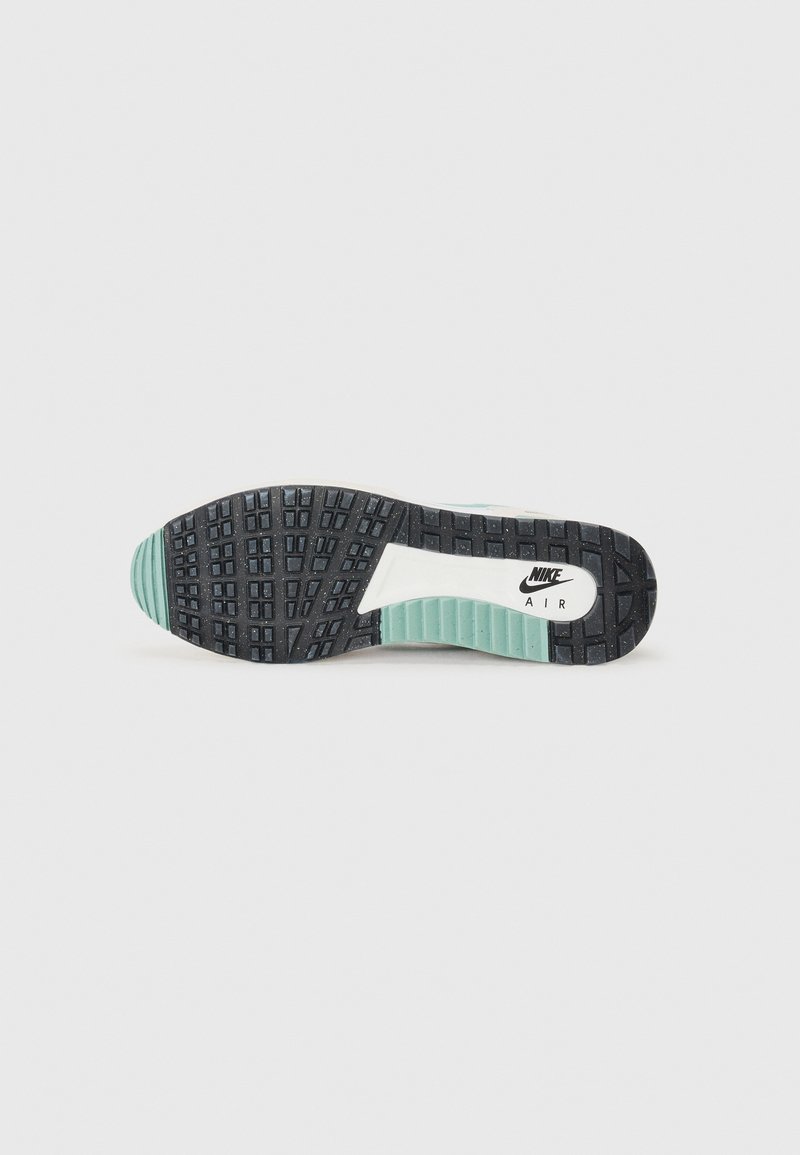 Black rubber shoe sole with textured grip pattern, featuring a white Nike Air logo in the center and mint green accents on the edges.