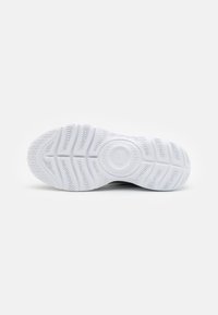 White athletic shoe sole with patterned tread, featuring a circular emblem at the center and smooth edges. Textured rubber for grip.