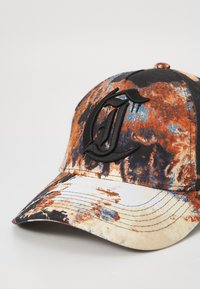 Căciulă cu un model tie-dye multicolor în nuanțe de portocaliu, negru și albastru, având un logo brodat negru în față și un vizor curbat.