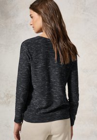 Schwarzer, strukturiertes Sweatshirt mit langen Ärmeln, rundem Halsausschnitt und einem leicht lockeren Schnitt. Verfügt über ein dezentes Melange-Muster und einen gerippten Saum.