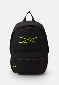 Mochila negra hecha de un tejido duradero, con un logotipo amarillo neón, un bolsillo frontal con cremallera que tiene un pequeño acento verde y una forma clásica.