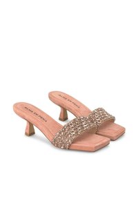 Le mules con tacco in suede rosa presentano una larga fascetta decorata con elementi metallici. I tacchi sono corti e di forma quadrata per un design moderno.