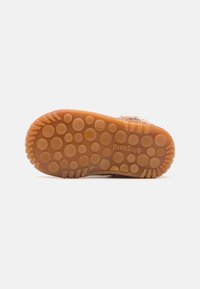 Semelle de chaussure en caoutchouc présentant une surface texturée avec des motifs circulaires, de couleur marron clair, et une inscription de marque bien visible. Conception durable et flexible.