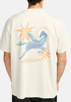 Crème-kleurige katoenen T-shirt met een grafische afbeelding van een blauwe gevleugelde paard, omringd door oranje steraccenten en zachte texturen in een speelse vormgeving.