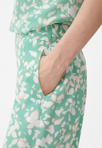 Bloemmotief outfit in muntgroen met witte en perzikkleurige accenten; heeft een losse pasvorm en een zijzakdetail. Gladde stoftextuur.