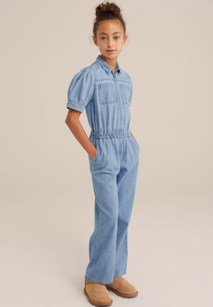 Kortärmad denimjumpers i ljusblått med spridd krage, elastisk midja och två bröstfickor. Bärs med bruna ankelstövlar.