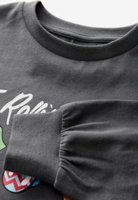 Grauer Sweatshirt mit geripptem Rundhalsausschnitt, versammelten Ärmelaufschlägen und bunten Druckgrafiken mit unterschiedlichen Mustern auf der Vorderseite.