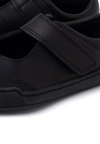 Zwarte leren schoenen met een gesloten neus, klittenbandsluiting, gestructureerde zool en uitsparingen voor ademend vermogen.