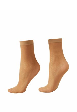 Par de calcetines tobilleros transparentes de color beige con un patrón sutil de diamantes y puños elásticos sólidos, exhibidos en maniquíes transparentes de pie.