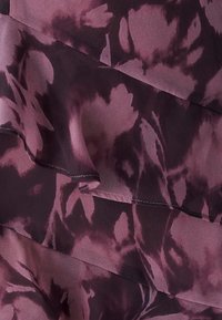 Priehľadná, vrstvená látka s kvetinovým vzorom v odtieňoch purpurovej a tmavofialovej. Mäkká textúra s zaoblenými hranami a viditeľným prešívaním.