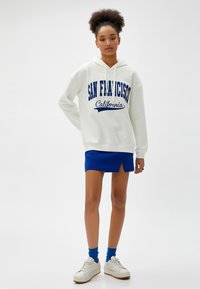Jasny hoodie z napisem "San Francisco California" w granatowym kolorze. Połączony z niebieską mini spódnicą, białymi tenisówkami i niebieskimi skarpetkami.