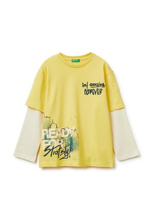 Geel langarm T-shirt met witte mouwen, bedrukt met de tekst "Feel amazing FOREVER" en "READY FOR Street Style" en een stadsgezicht als afbeelding.