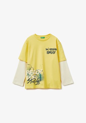 T-shirt superposé jaune à manches longues avec manches blanches, texte imprimé « Feel amazing FOREVER » et « READY FOR Street Style » avec graphisme de paysage urbain.