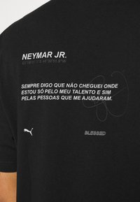 Svart bomull t-skjorte med hvit tekst som detaljerer Neymar Jr., koordinater og et sitat. Inkluderer en liten hvit Puma-logo.