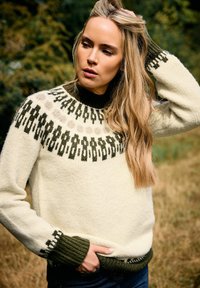 Cremfarbener, gestrickter Pullover mit einer dunkelgrünen gemusterten Passe. Verfügt über gerippte Bündchen und Saum in Dunkelgrün sowie eine strukturierte Oberfläche.