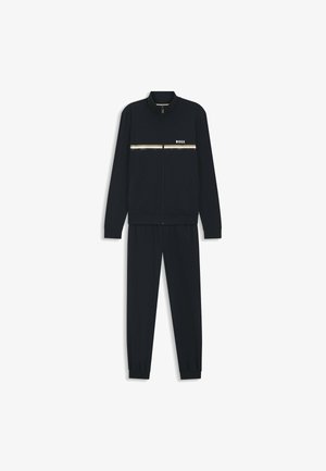 Survêtement noir pour homme avec veste zippée ornée de bandes horizontales dorées et blanches et logo "BOSS", assorti à un pantalon fuselé.