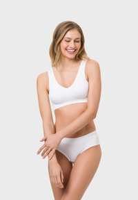 Weißer kabelloser BH mit breiten Trägern und V-Ausschnitt, kombiniert mit passenden tief sitzenden Slips. Glatte Textur, minimalistisches Design.