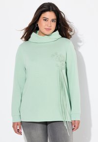 Felpa verde chiaro con collo a cappuccio, caratterizzata da un ricamo floreale e strisce pendenti sulla parte anteriore. Maniche lunghe e texture morbida.