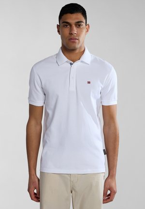 Weißes Poloshirt mit klassischem Kragen, kurzen Ärmeln und einem kleinen Flaggenemblem auf der linken Brust. Hergestellt aus glattem Baumwollstoff.